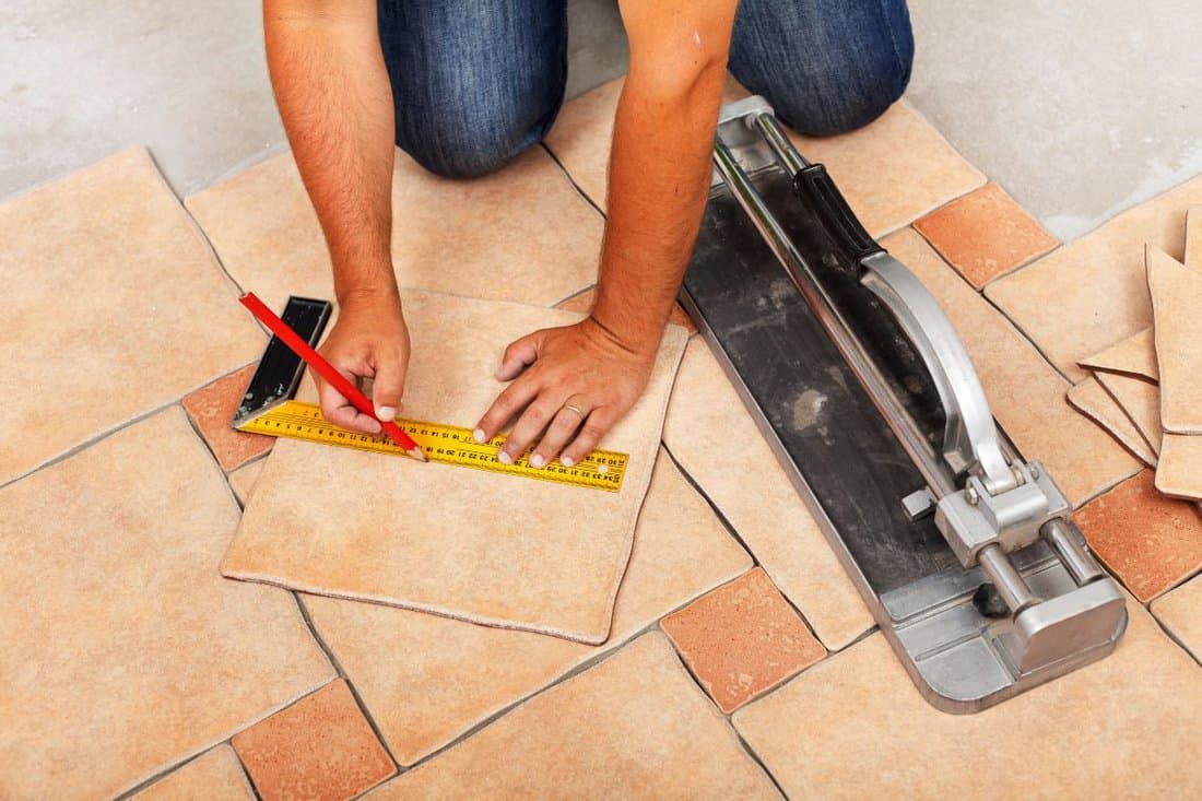 Installing ceramic floor tiles - measuring and cutting the pieces, closeup