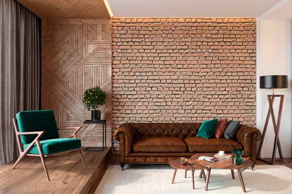 Modern living room interior with brick wall blank wall, leather brown sofa, green lounge chair, table, wooden wall and floor, plants, carpet, hidden lighting