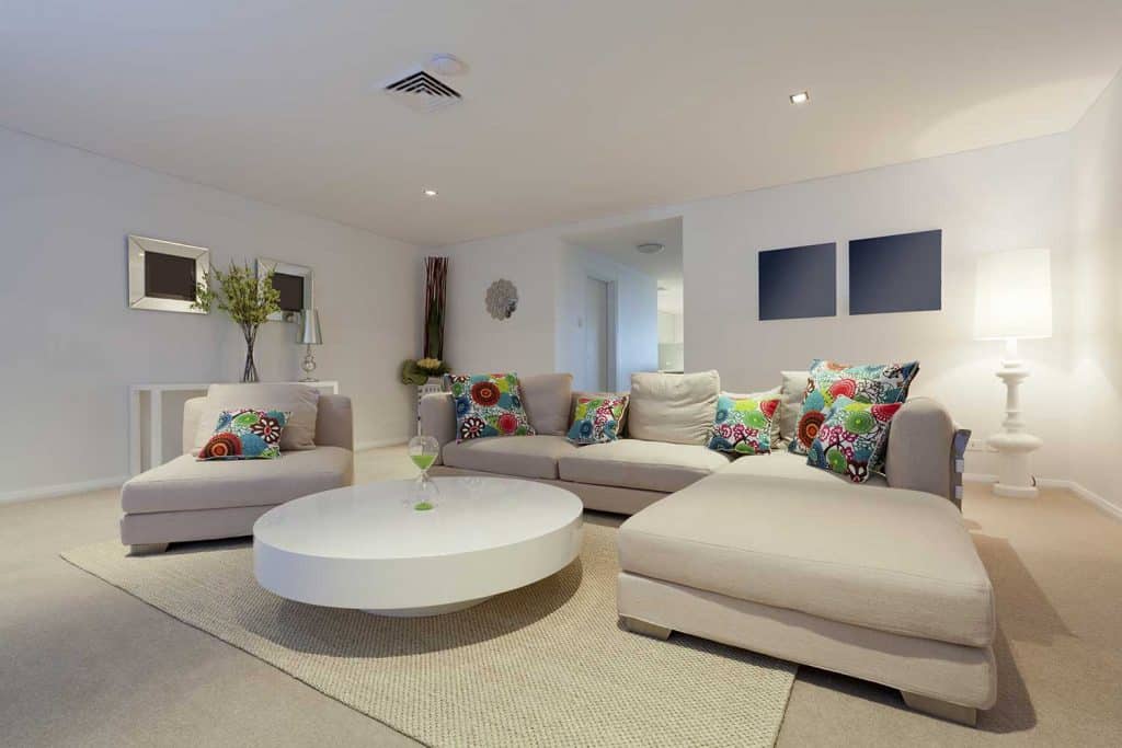 Salon moderne avec canapé d'angle, tapis et table ronde blanche