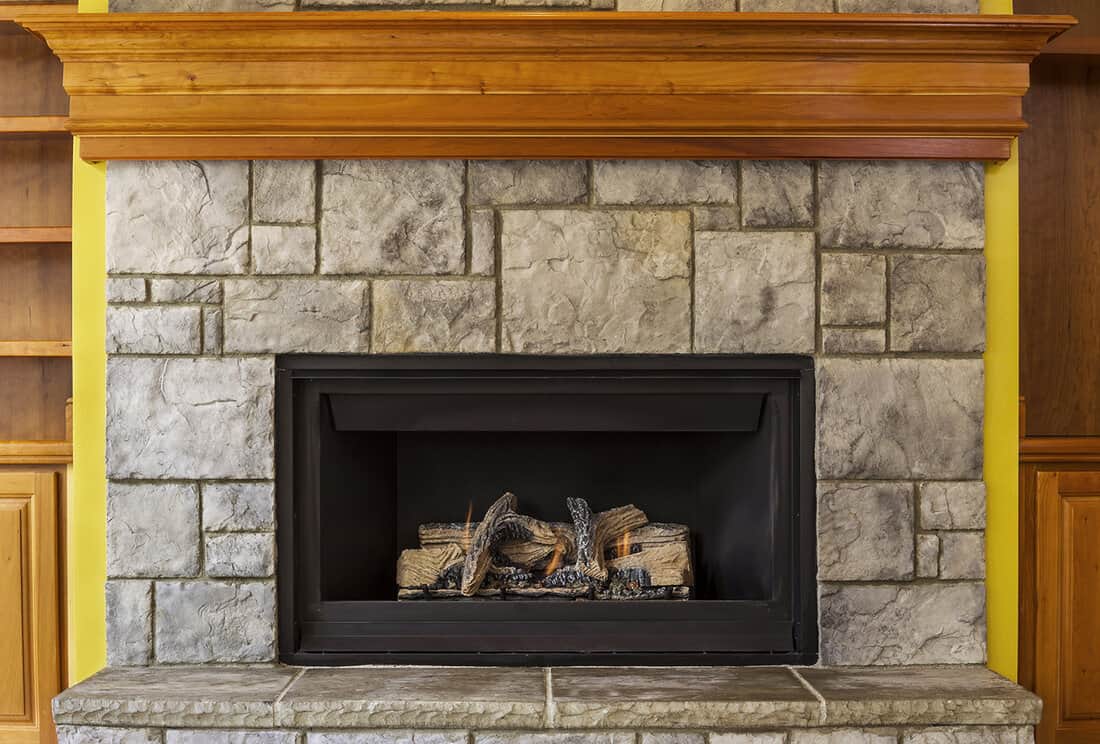 Natural gas insert fireplace built with stone and wood