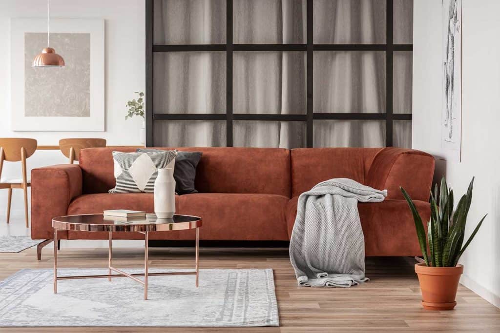 Canapé d'angle marron élégant avec oreillers à motifs dans un intérieur élégant de salon avec mur à meneaux