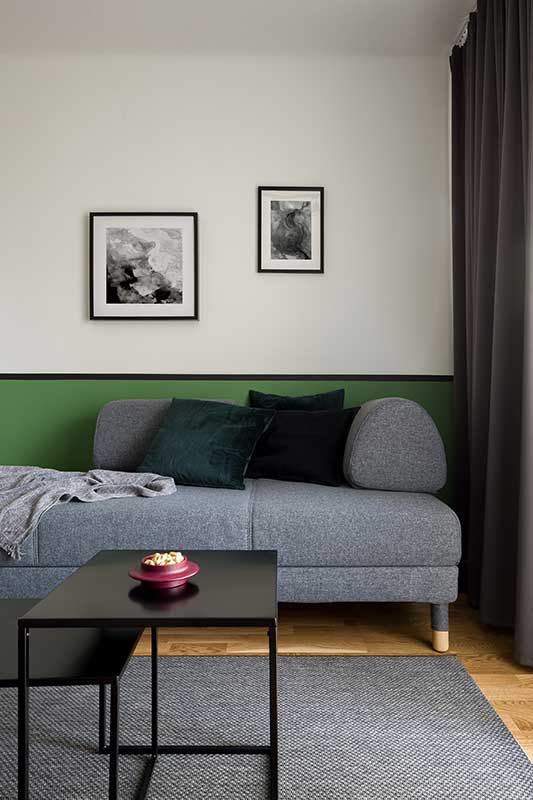 Canapé gris élégant et deux tables basses noires sur tapis gris dans une chambre moderne