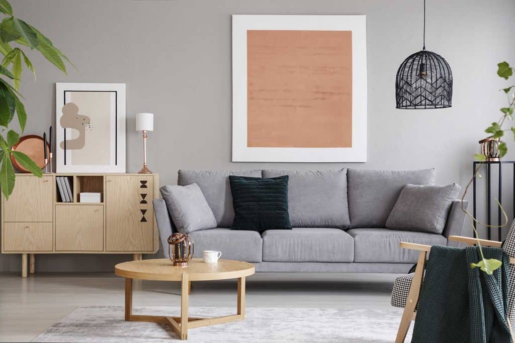 Placard en bois à côté d'un canapé dans un intérieur de salon moderne avec un grand tableau