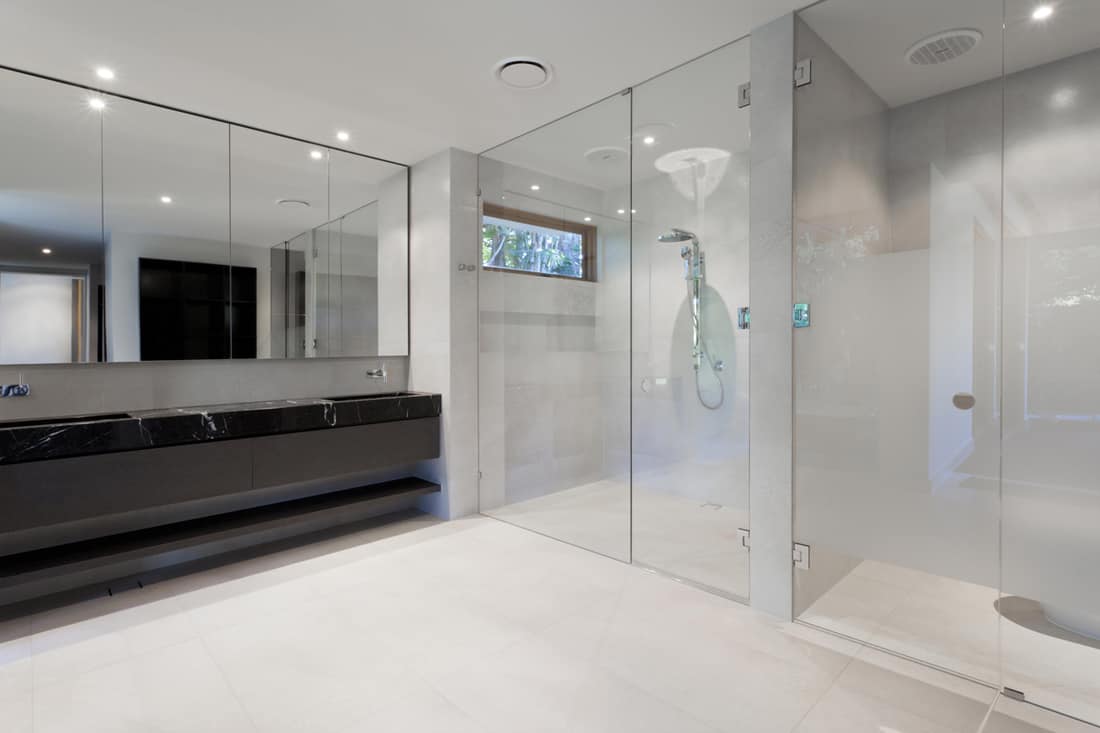A modern bathroom with a dark marble countertop in the lavatory section and frameless shower door, Do Frameless Shower Doors Leak?