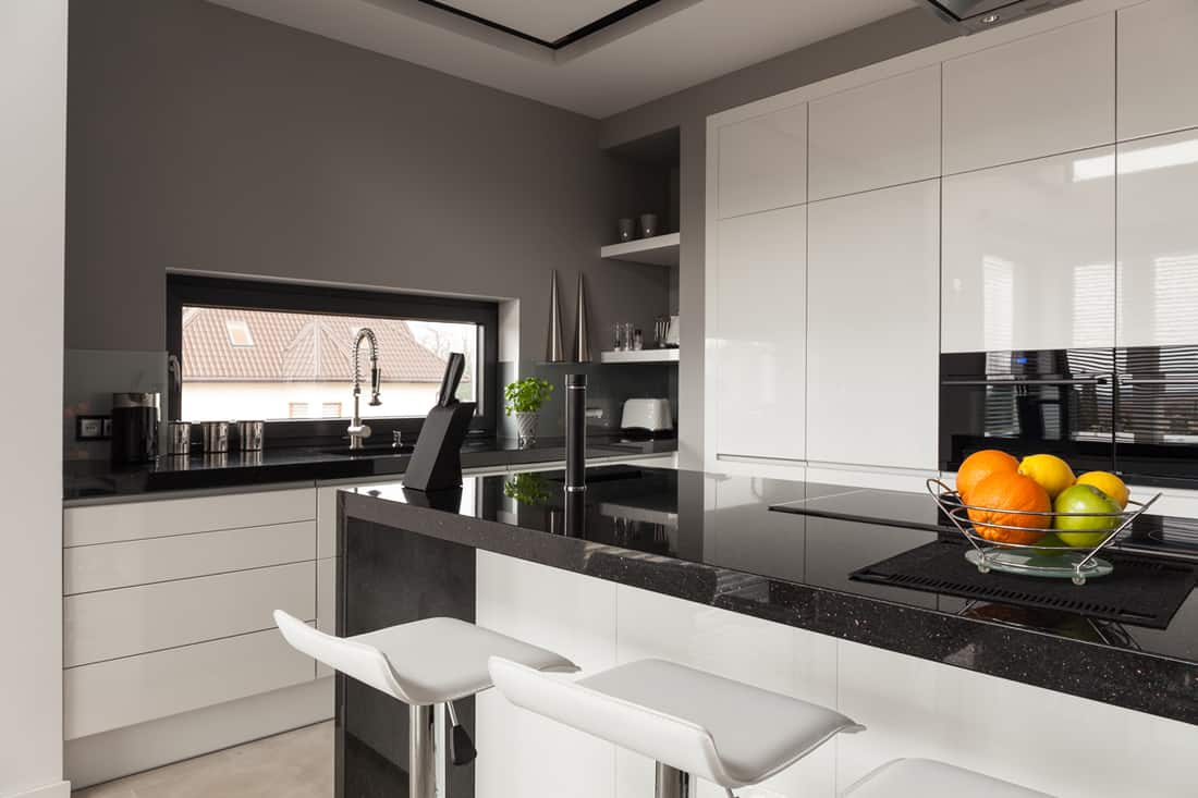 A modern kitchen with white paneled cabinets mixed with black granite countertops