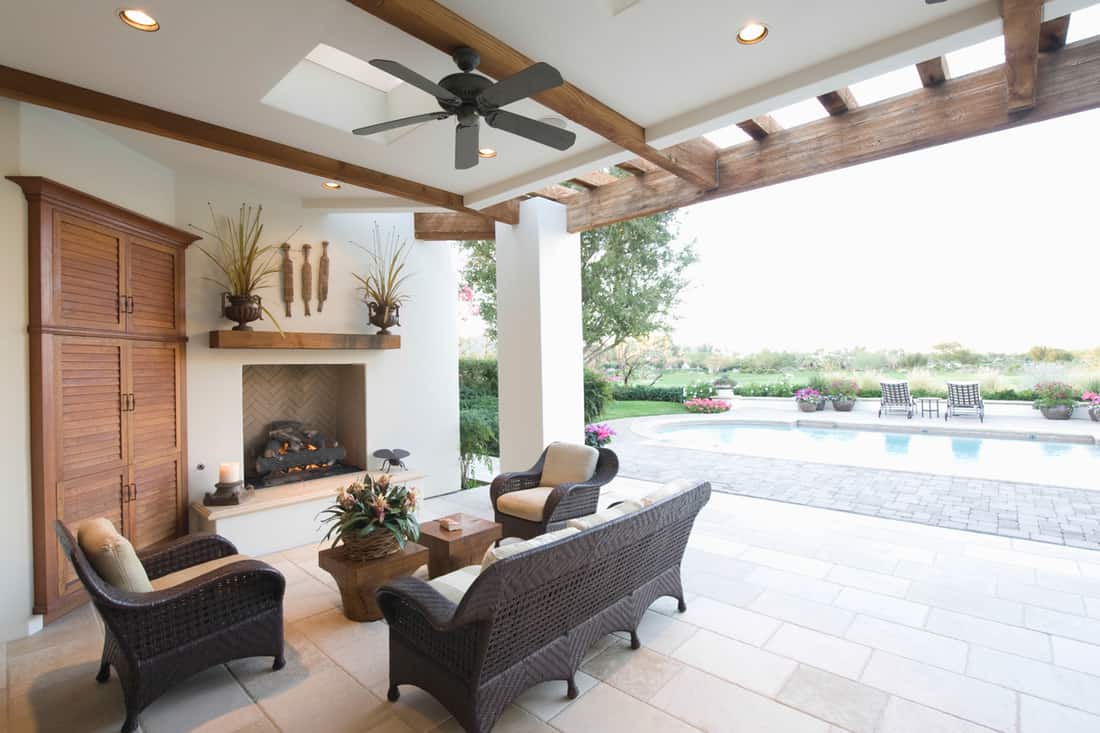 Tropical house with an outdoor pool, rattan chairs, a white painted ceiling with a black colored ceiling fan, Should the Ceiling Fan Match the Ceiling Color?