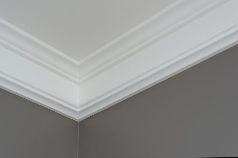 A white colored crown molding on a gray wall, Should Crown Molding Be Painted Flat or Semi-Gloss?