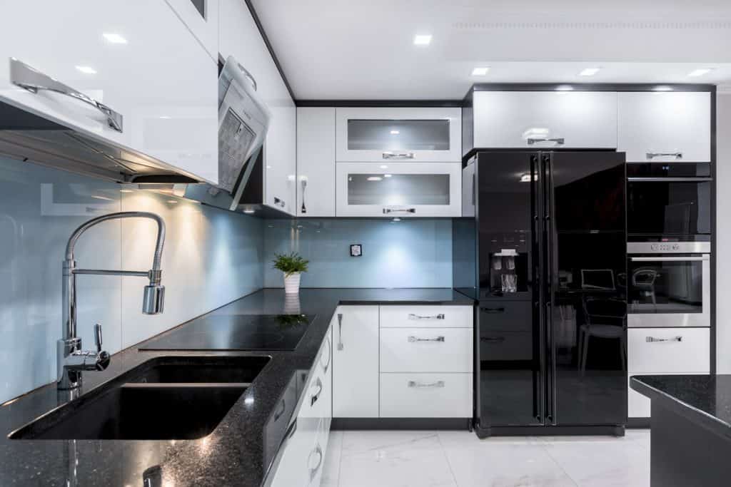 An ultra modern kitchen with black granite countertops and white paneled cabinets