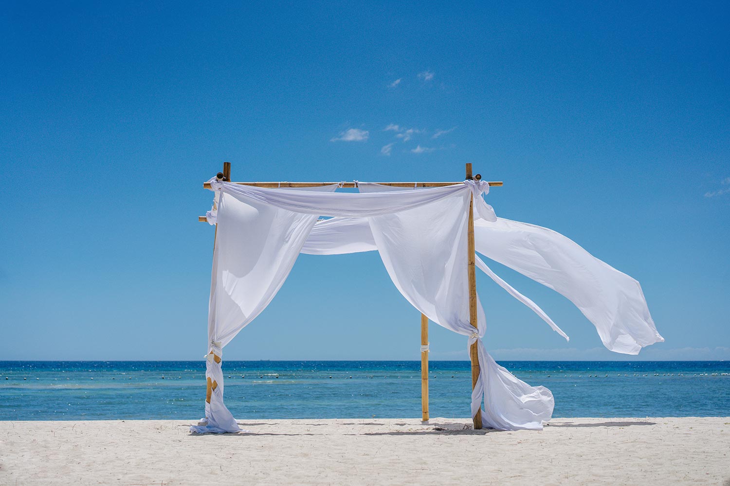 Beach shade with white gracefully fluttering fabric curtains on seashore