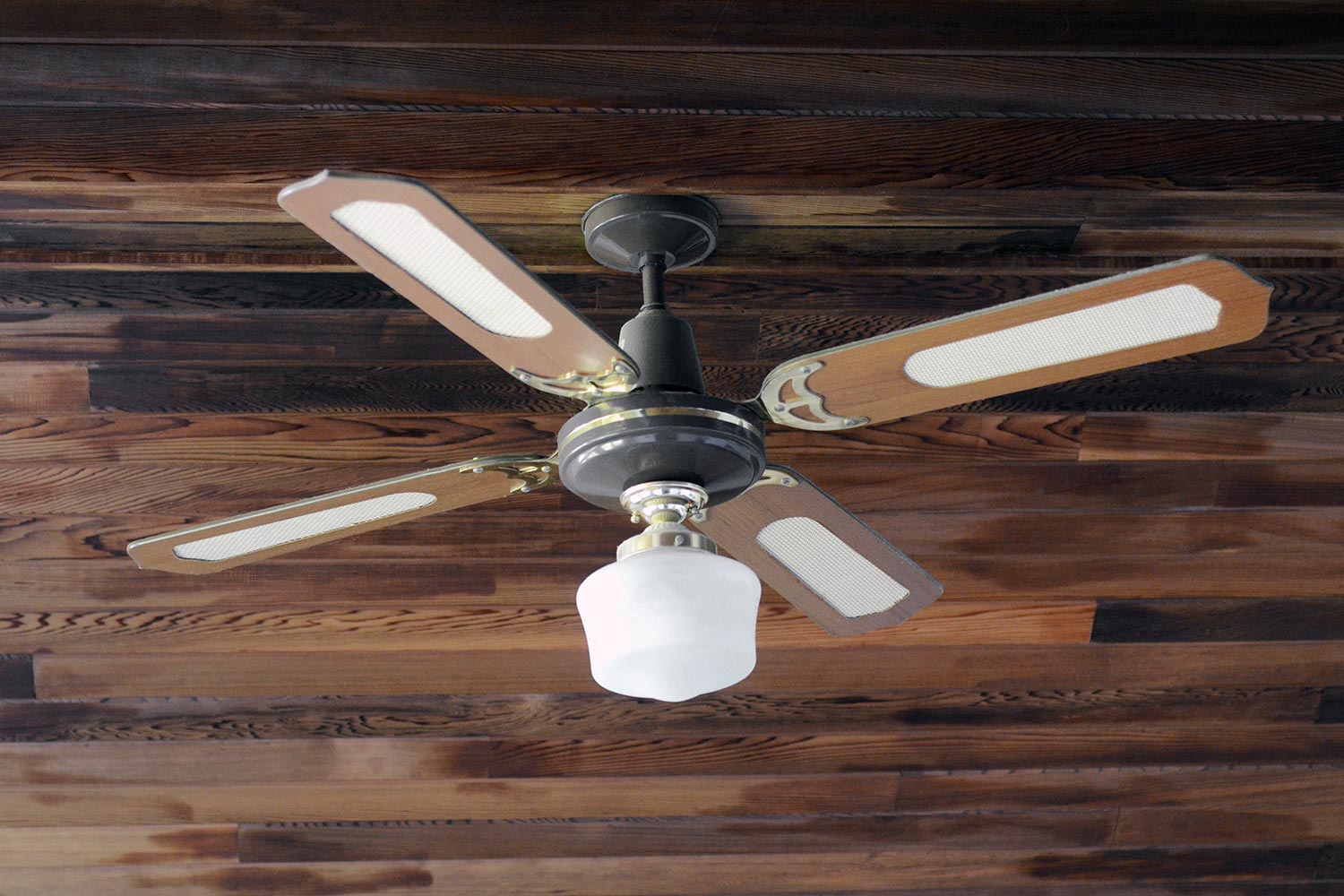 Closeup of a ceiling fan in a vaulted ceiling from the 1980s.