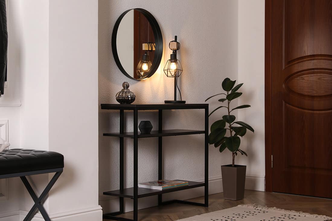 Console table with decor and mirror on white wall in hallway
