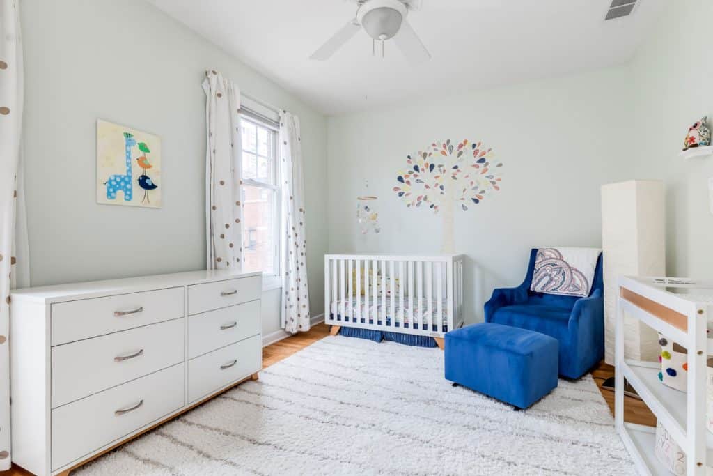Interior of a nursery room with white painted walls, white cabinets and white carpet