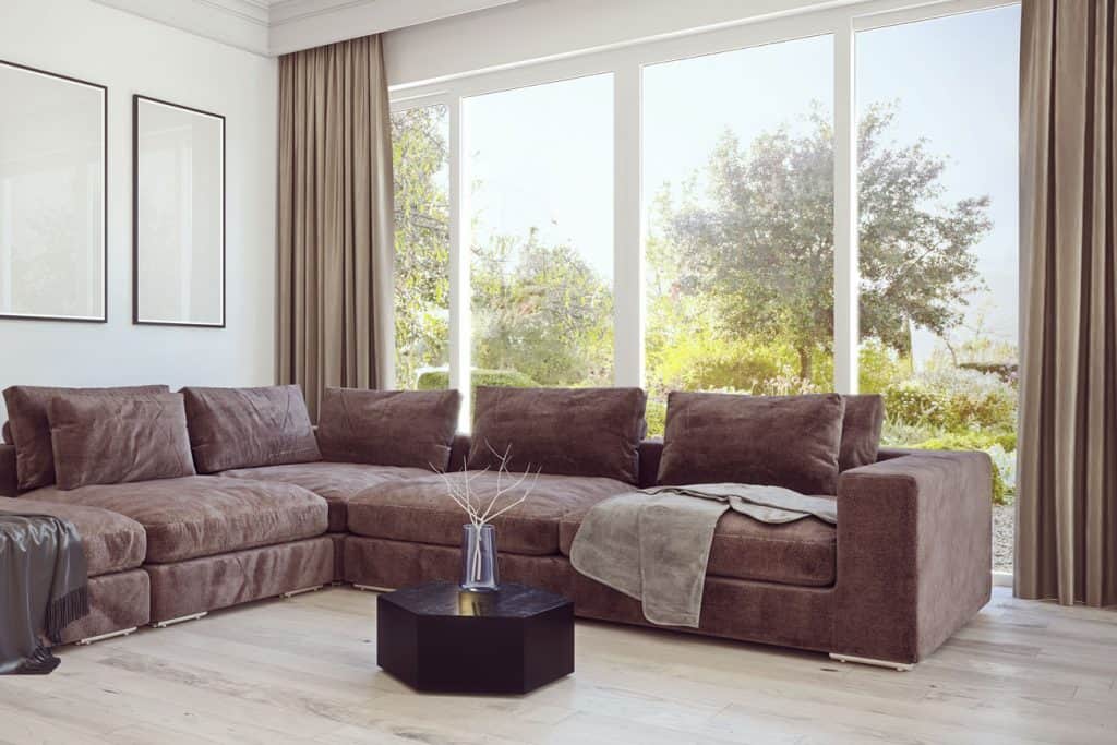 Modern design living room in countryside with brown curtains and beautiful garden in background