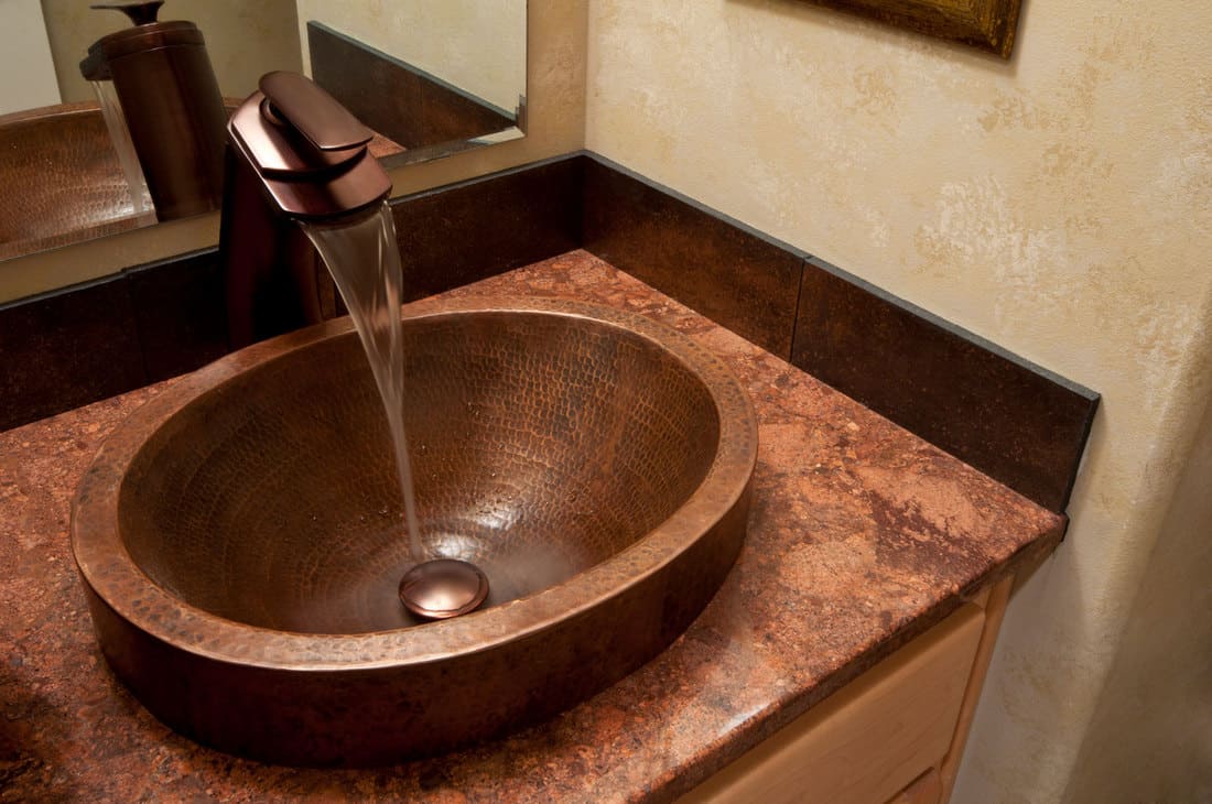 Ceci est un gros plan d'un lavabo de salle de bain en cuivre bronze.