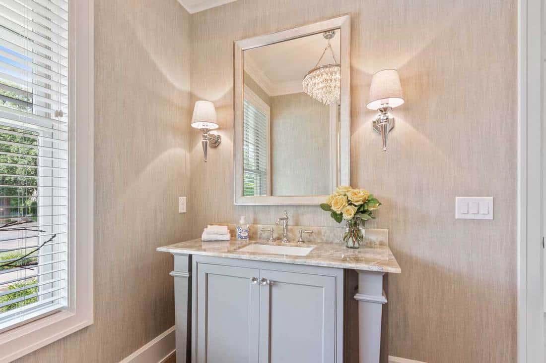 Wall sconce on each side of mirror in lovely powder room