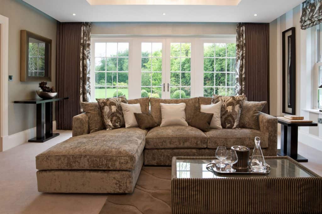 A gorgeous lounge in a luxury new home dressed in shades of brown, beige and bronze with brown curtains