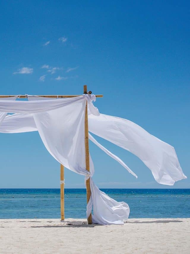 Beach shade with white gracefully fluttering fabric curtains on seashore