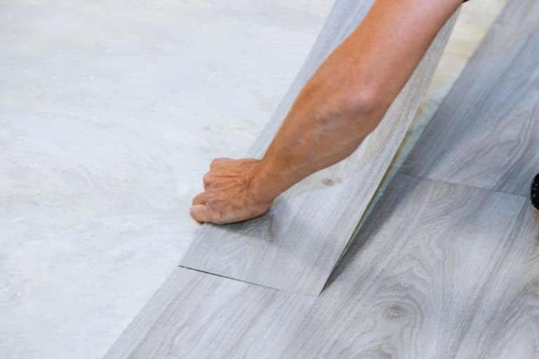 Man installing vinyl laminate flooring on the bathroom floor, Vinyl Flooring in The Bathroom: Pros and Cons
