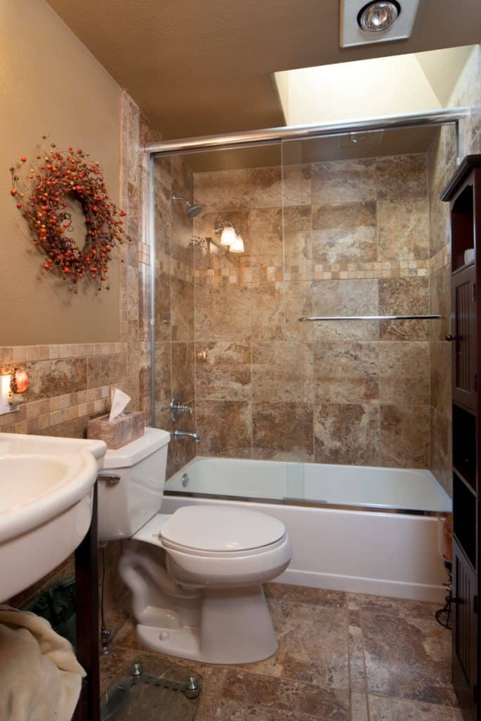 Beyaz kahverengi fayanslar, kahverengi duvarlar ve cam duş duvar alanı içeren modern bir banyo