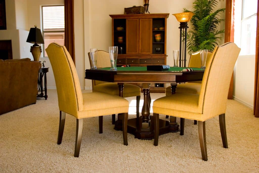 A poker table with cards on the table and four yellow chairs