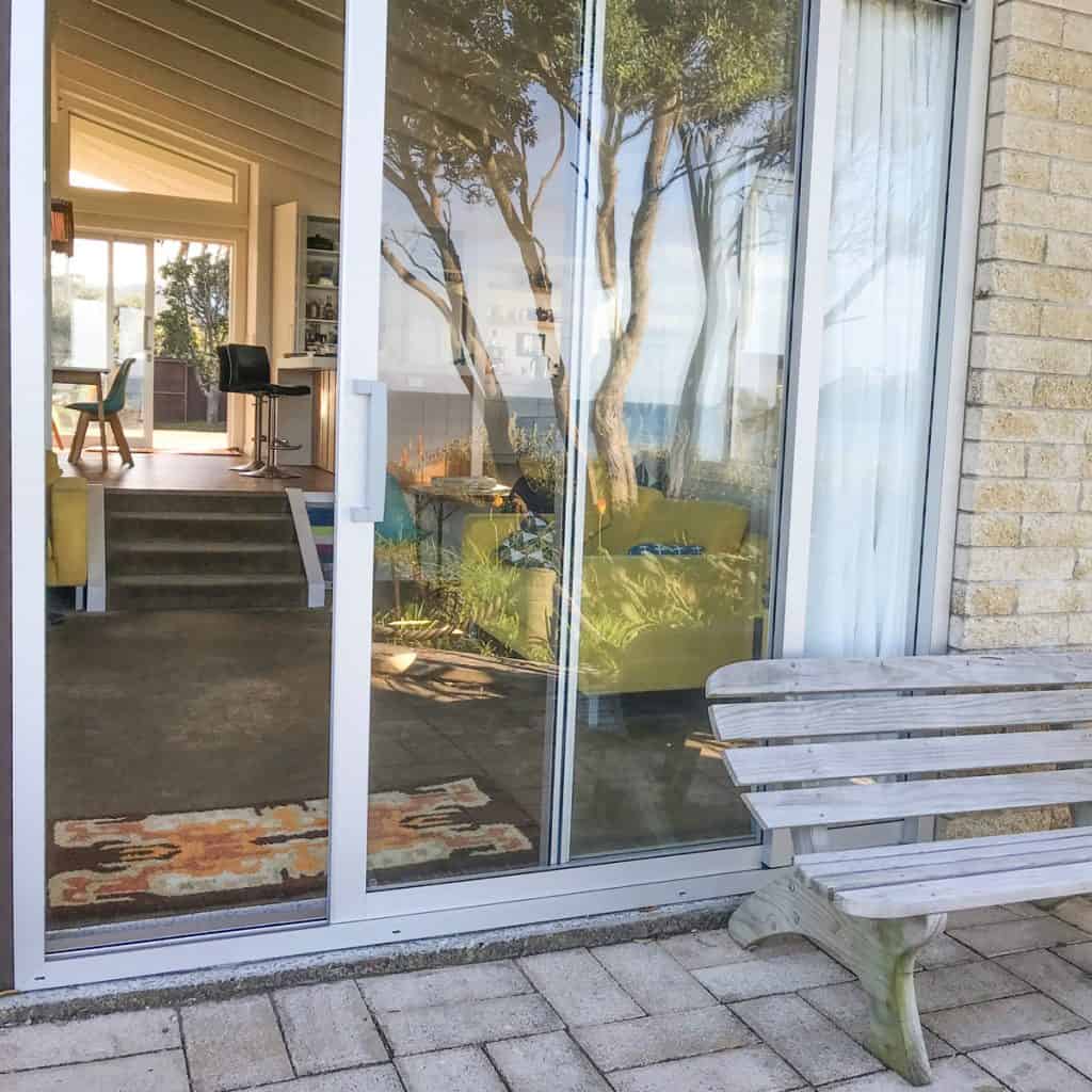 A sliding glass door of a farmhouse near a patio