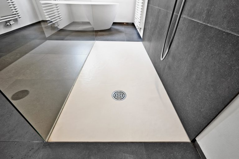 A small shower drain of a modern bathroom with white brown and gray colored tiles, Should A Shower Drain Match The Tiles?