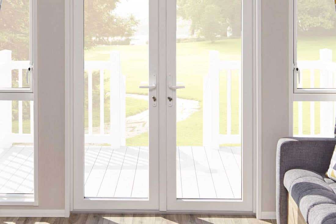 A white french door entrance to a living room with view of the front yard, How to Hang Roman Shades on French Doors [5 Steps]
