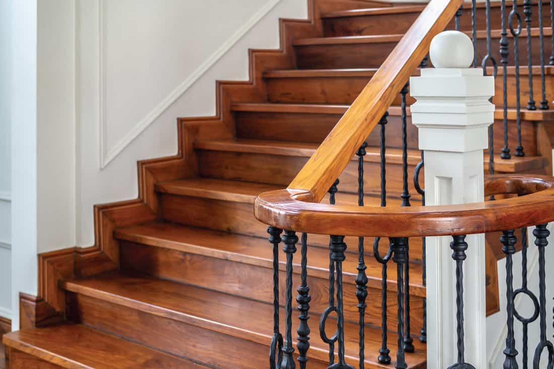 Classic vintage elegant wooden staircase with wrought iron railing