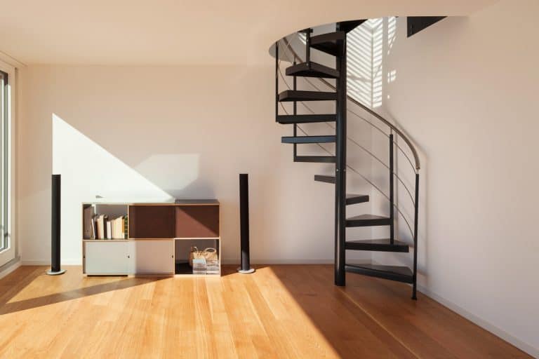 An empty living room with spiral stairs and wooden floor, Does A Spiral Staircase Save Space?