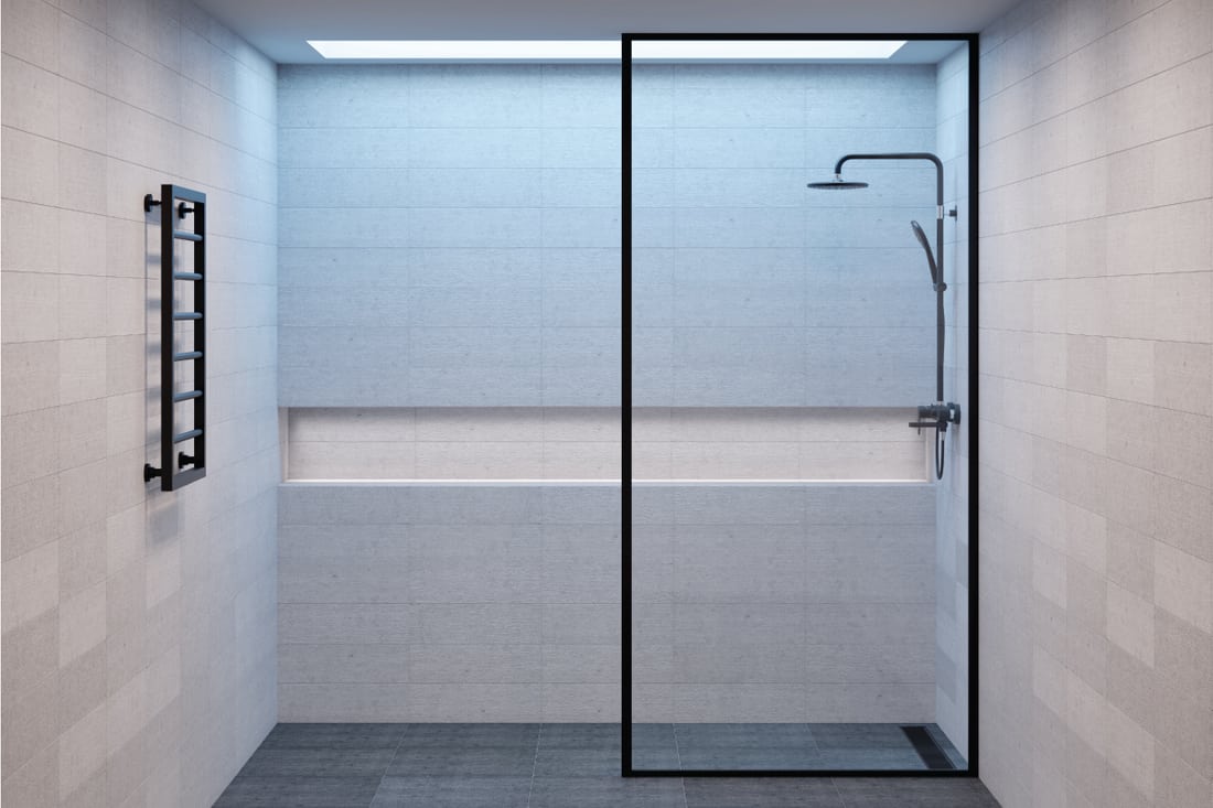 Empty minimalistic shower room with a window in the ceiling, a niche for bath accessories and a heated towel rail, Is the Shower Door Glass Typically Tempered?