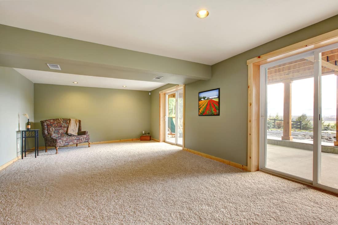 Ground level of a large new living room with green walls and carpet in doorway, Where Should Carpet End In A Doorway? Important Information to Know!