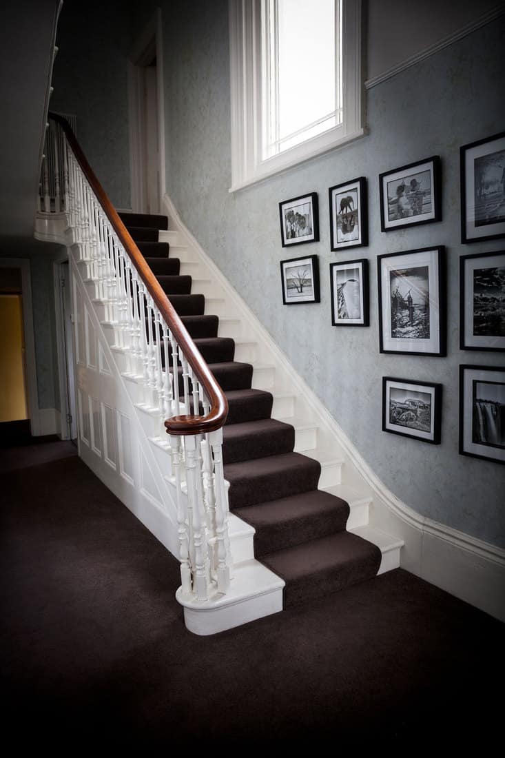 Hall and stairs of a victorian home with hanging wall art