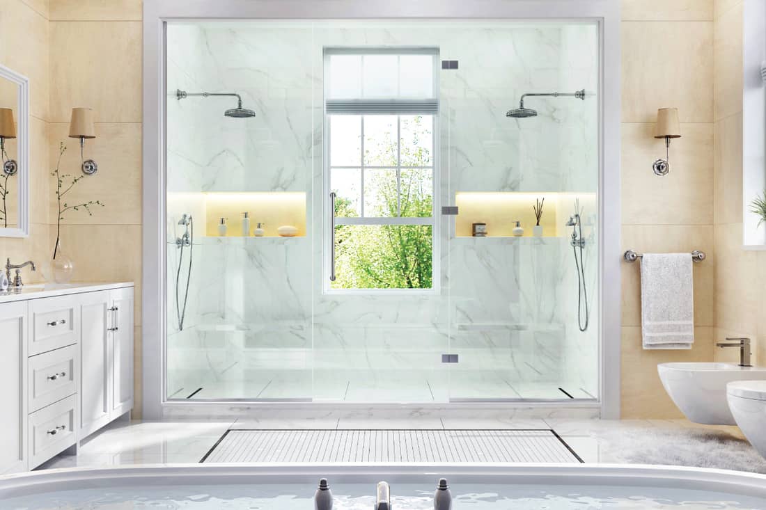 Salle de bain luxueuse avec baignoire, grande douche et fenêtre.
