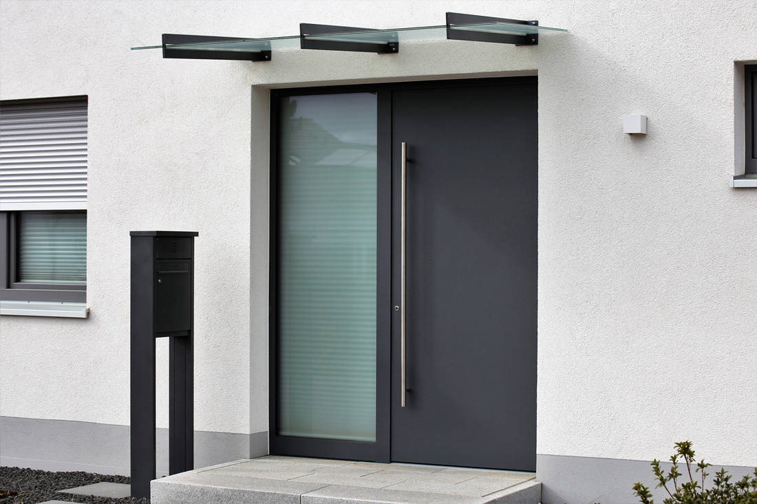 A modern contemporary house with a steel door and a glass steel framed awning, What Is The Safest Front Door? Here's the Answer