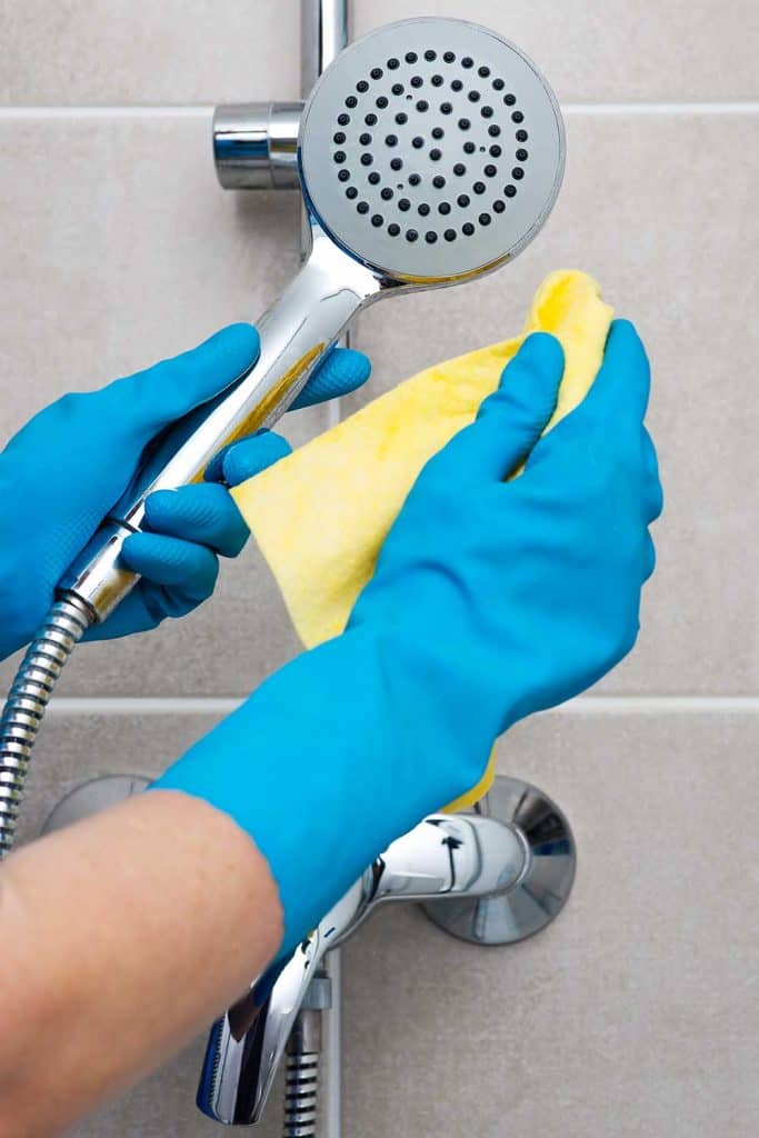 Personne portant des gants bleus nettoyant la salle de bain