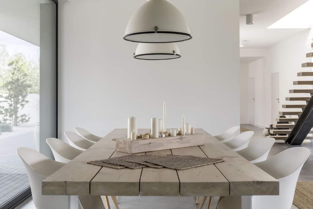 Room with wood dining table, white chairs and industrial lamp