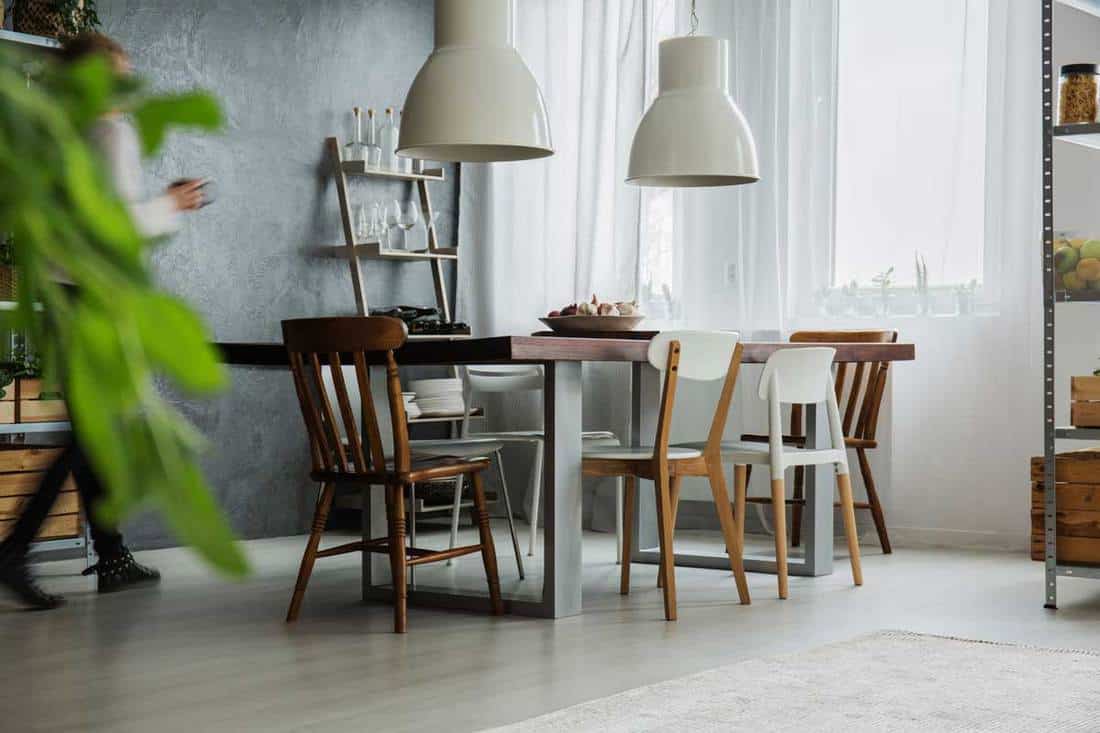 Table rustique, différentes chaises et mur sombre dans la salle à manger