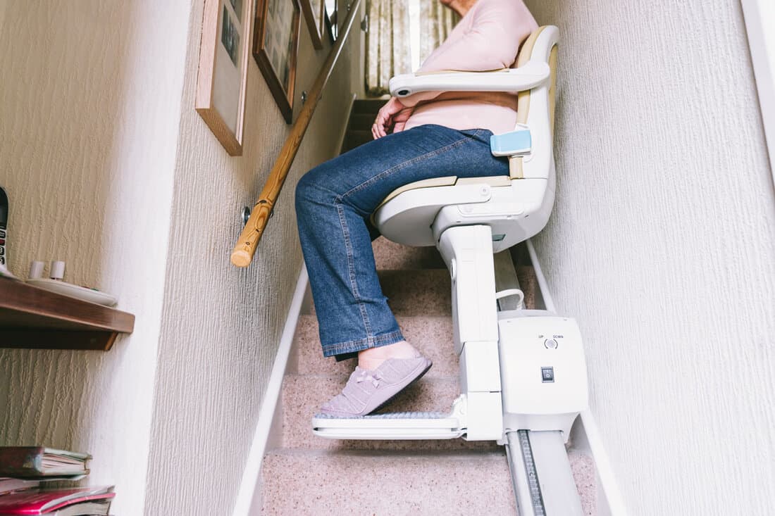 Senior woman using automatic stair lift on a staircase at her home