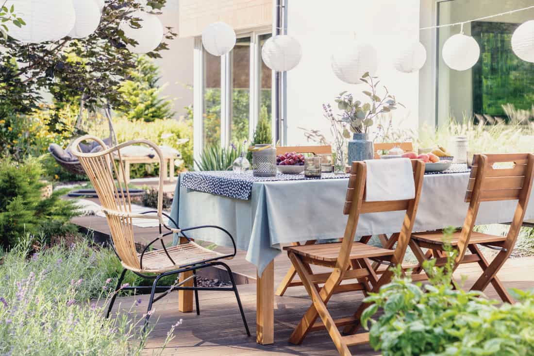 Tafel met houten stoelen in felgroene tuin van modern huis