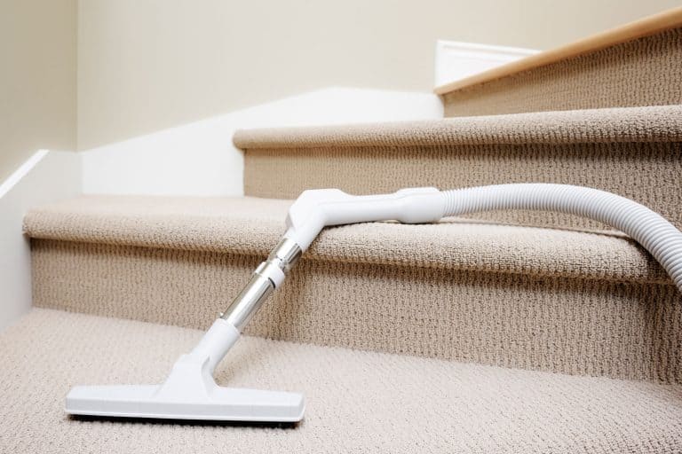 Vacuum cleaner lying down in stairway covered by carpet, domestic, How To Clean Carpet On Stairs [Even Without A Machine]