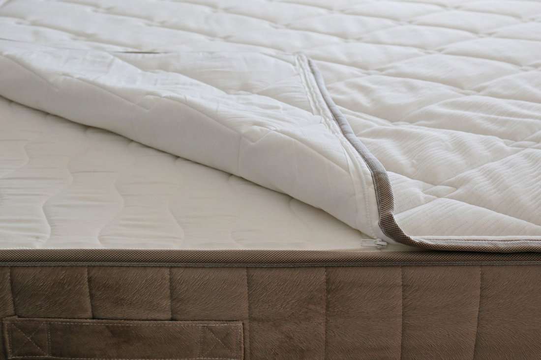 White orthopedic mattress top side surface pattern on unmade bed in the bedroom. Hypoallergenic foam mattress for proper spinal alignment and pressure