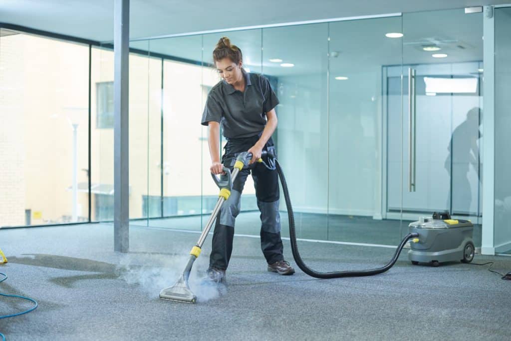 A female cleaning contractor cleaning an office carpet