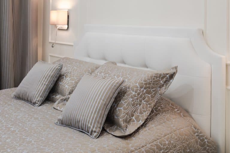king size white bed decorated with brown pillows, How Wide Is A Bed Headboard [For King, Queen, Double, And Twin Beds]