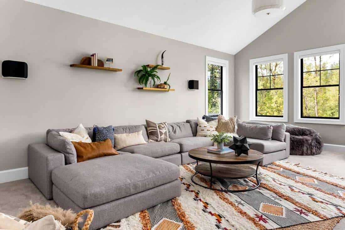 A living room with gray corner sofa in newly constructed luxury home, Should Throw Pillows Match The Rug?