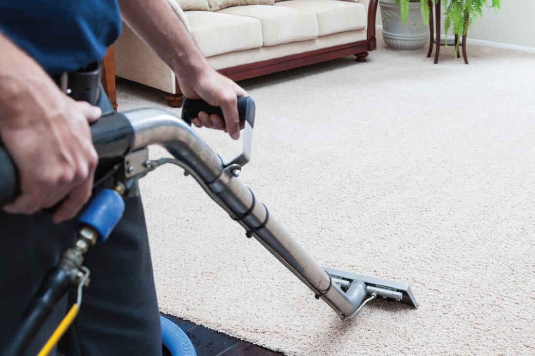 Man holding a high performance vacuum machine cleaning a carpet, Do You Tip Carpet Installers And Cleaners?