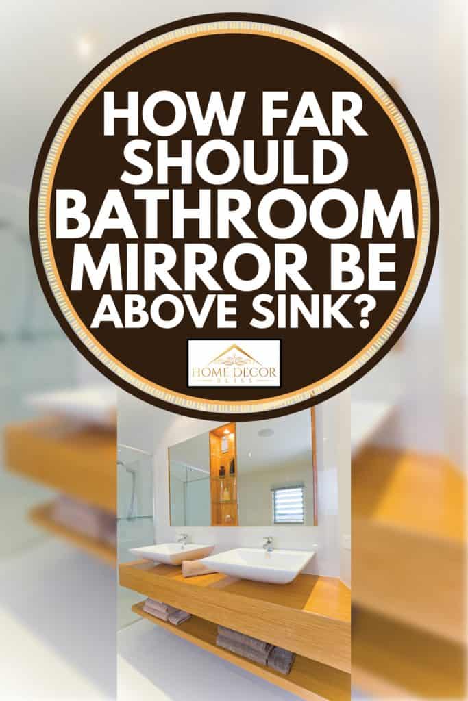 Salle de bain moderne avec comptoir marron accentué et miroir sans cadre, à quelle distance le miroir de la salle de bain doit-il être au-dessus du lavabo ?