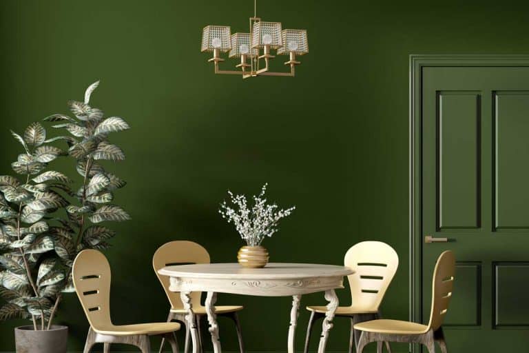 Modern dining room interior with wooden classic table and yellow chairs against dark green wall, How Big Should A Dining Room Chandelier Be?