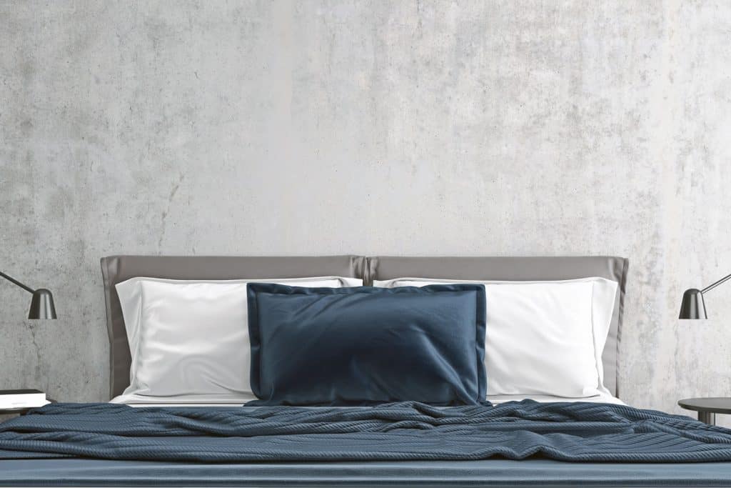 A bed with blue and white beddings with a gray headboard