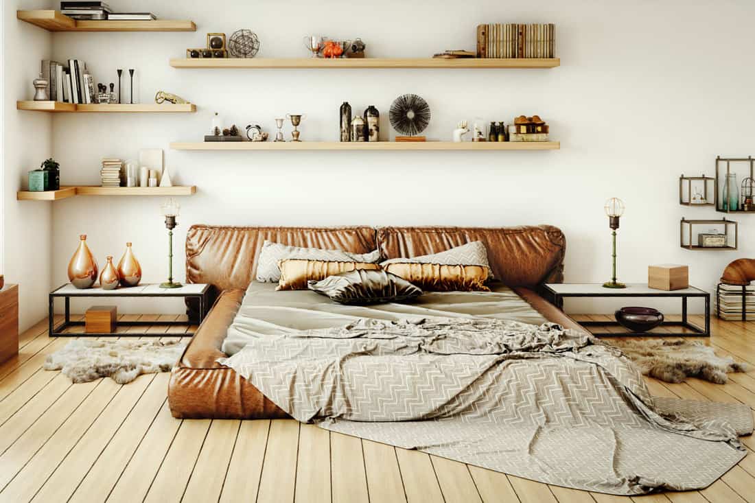 Brown leather bed with brown pillows and gray beddings with spacious shelves with books and figurines, What Color Sheets Go With A Brown Bed? [12 Great Options!]