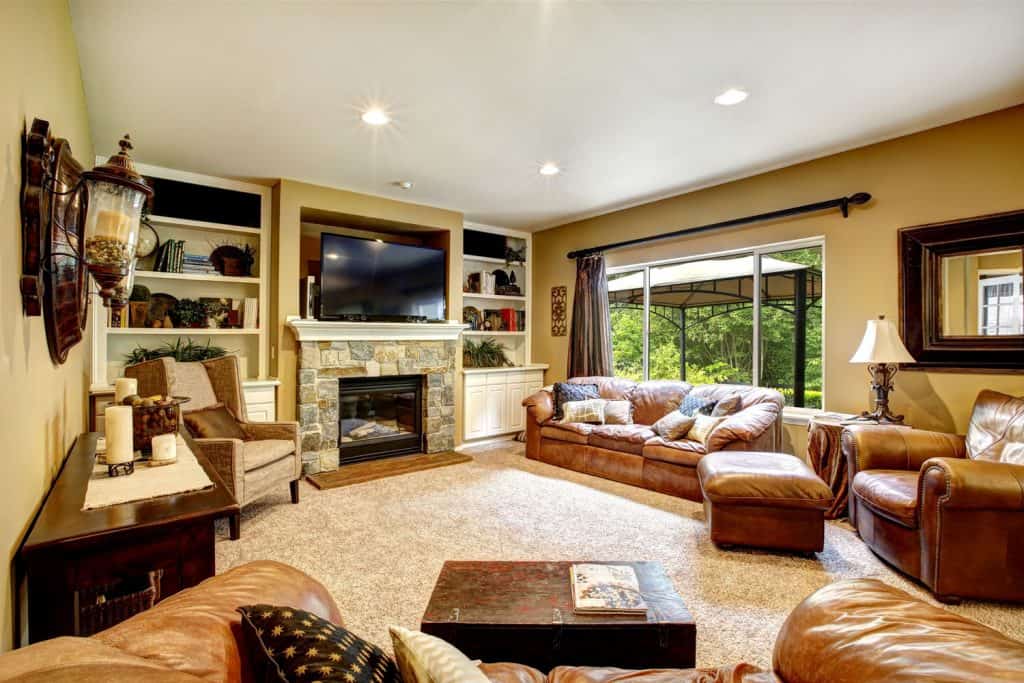 A classic themed living room with brown furniture and a light colored brown carpet